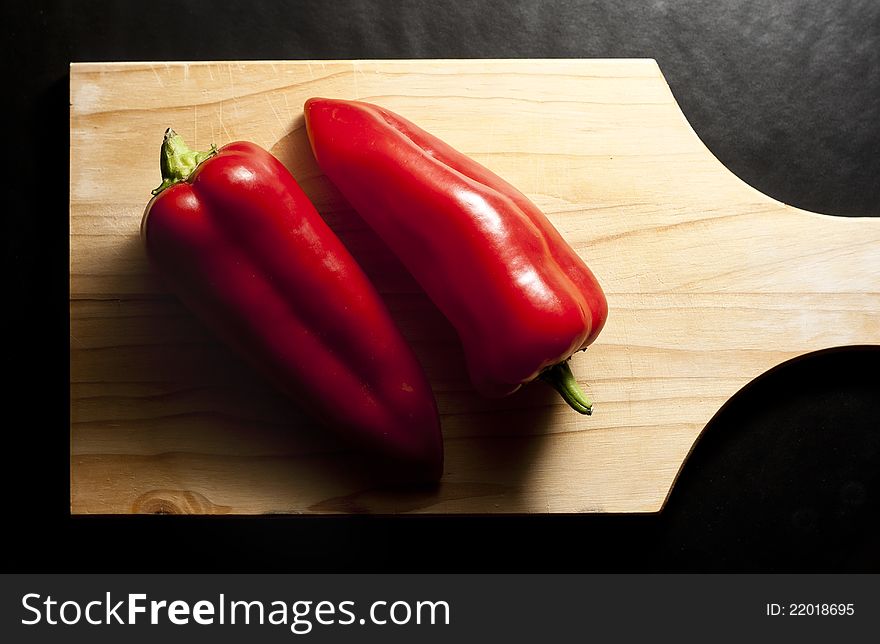 Two Red Peppers Set on a Wooden Board