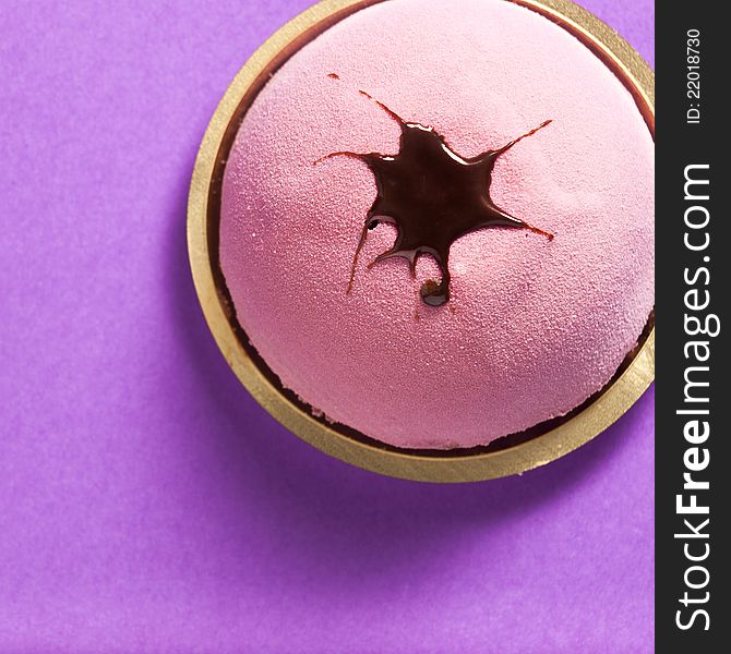 Close-up photograph of a round strawberry pastry set on a purple background