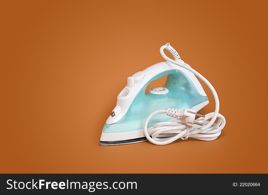 New modern electric iron with cable on nice brown background