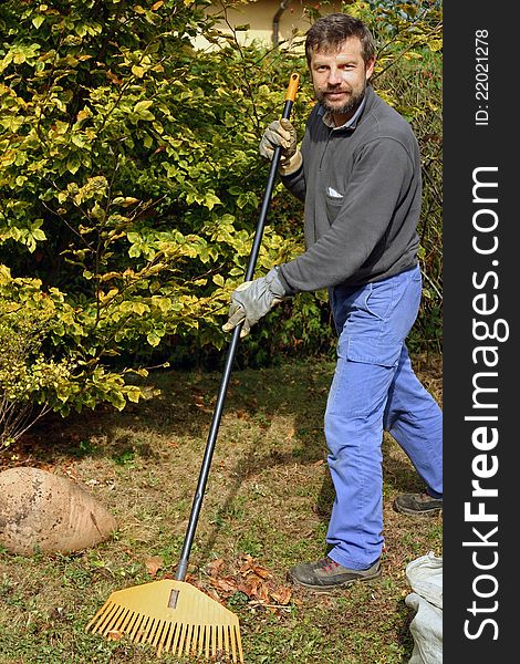 Likeable gardener cleaning outdoor from autumn leaves. Likeable gardener cleaning outdoor from autumn leaves