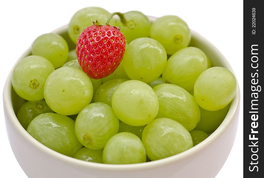 White cup filled with grapes and a strawberry. White cup filled with grapes and a strawberry