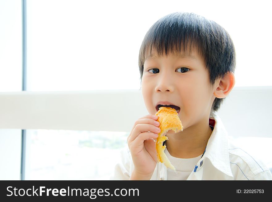 Asian boy eating a piece of pie and look at camera