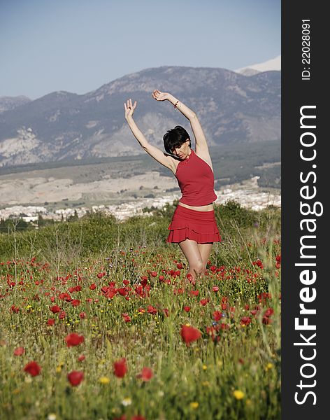 A girl dressed in red in a field of poppies in Granada, Andalusia, Spain