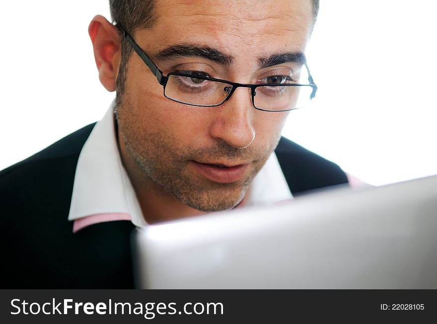 A successful businessman with glasses wearing vest and pink shirt looking at a little computer. A successful businessman with glasses wearing vest and pink shirt looking at a little computer