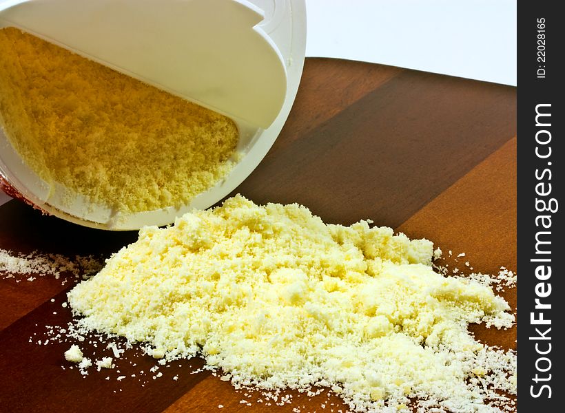 Container of dried parmesan on wooden board. Container of dried parmesan on wooden board.