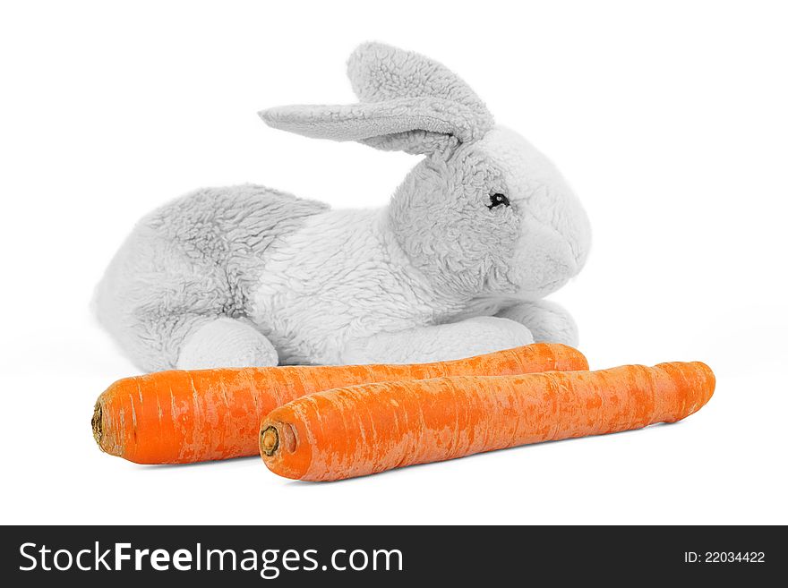 Carrots and a toy rabbit on a white background