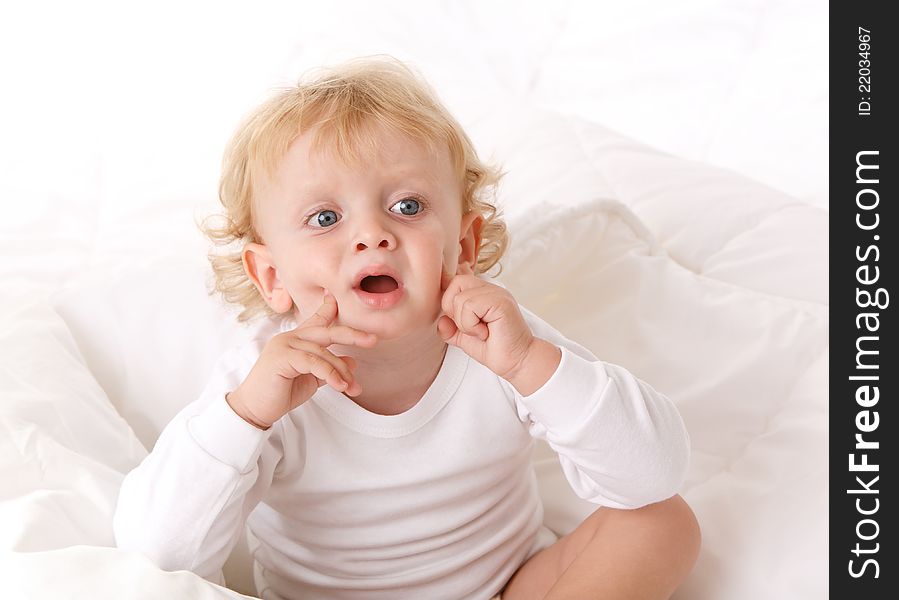 Little boy sitting on a white bed. Little boy sitting on a white bed