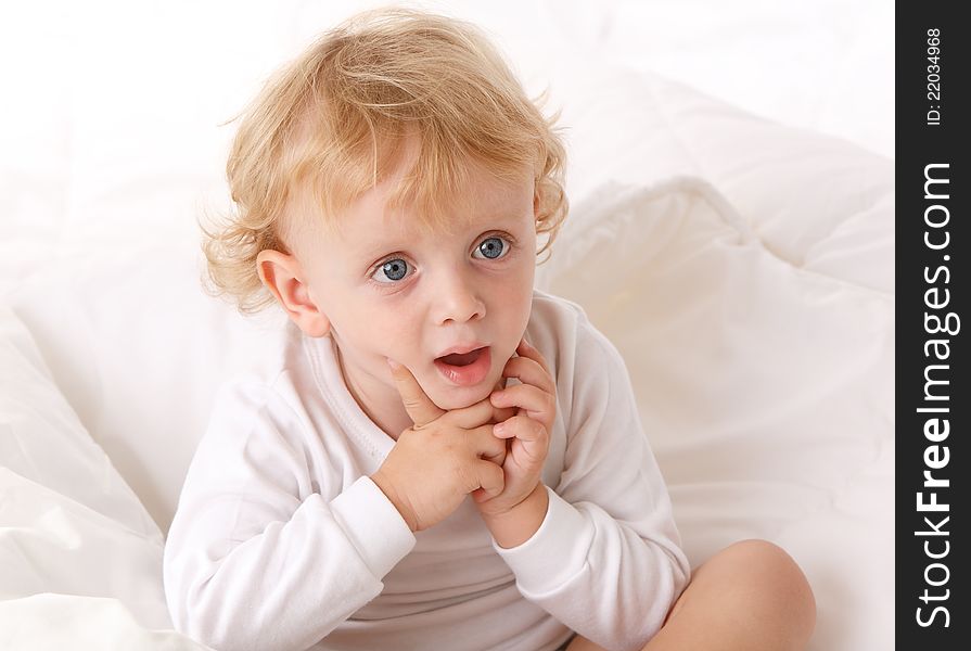 Little boy sitting on a white bed. Little boy sitting on a white bed