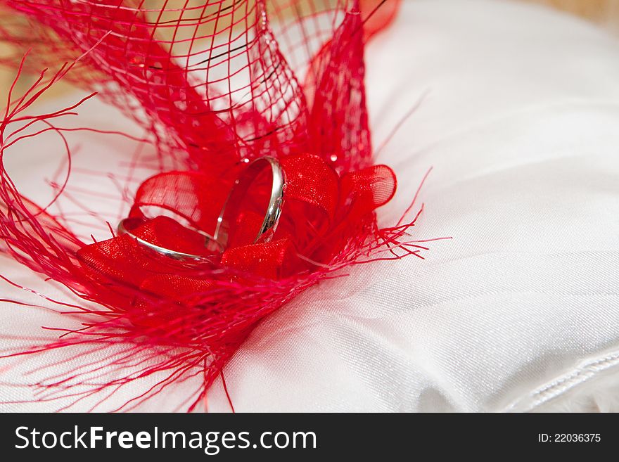Cushion with wedding gold rings in red feathers. Left position. Cushion with wedding gold rings in red feathers. Left position