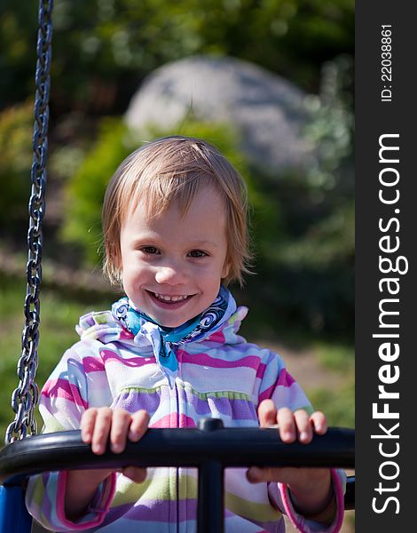 Portrait of smiling little girl on swing playground outdoors - looking at the camera. Portrait of smiling little girl on swing playground outdoors - looking at the camera