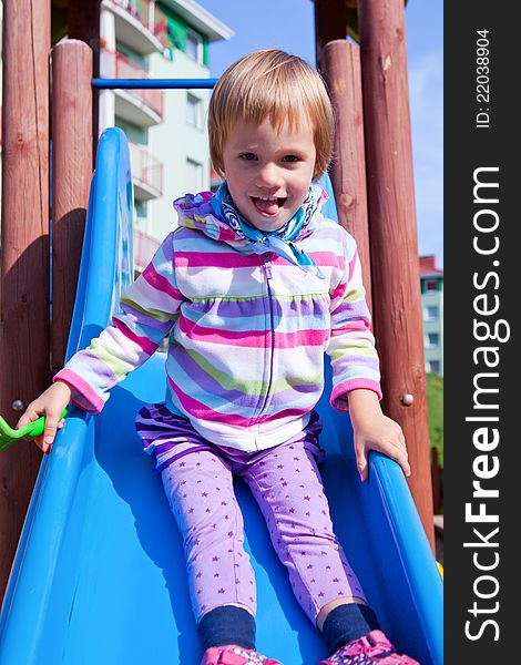 A young child enjoys a day at the playground as she slides down the colorful slide with a smile on her face. A young child enjoys a day at the playground as she slides down the colorful slide with a smile on her face