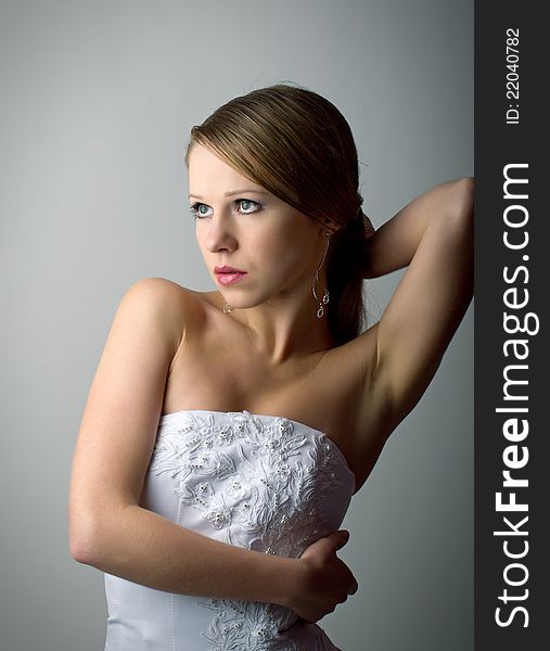 Beautiful charming young woman in white corset on a gray background