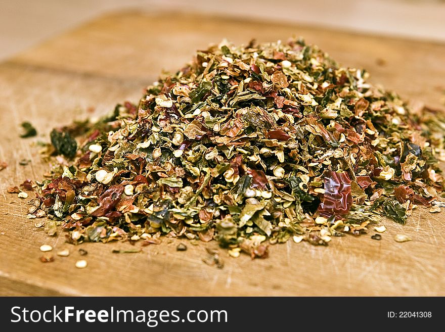 Dry red pepper flakes on wooden background