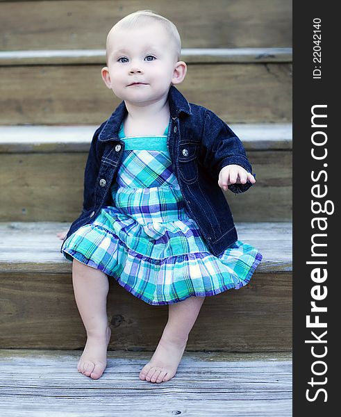 A one year old baby girl sitting on stairs. A one year old baby girl sitting on stairs.