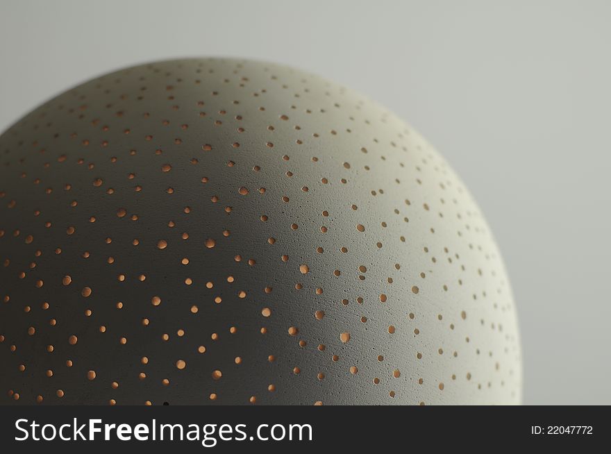 A modern ball shaped pierced ceramic candle holder. A modern ball shaped pierced ceramic candle holder