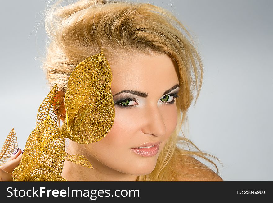 Beautiful green-eyed girl with blonde hair and professional make-up holding artificial golden calla lily. Beautiful green-eyed girl with blonde hair and professional make-up holding artificial golden calla lily