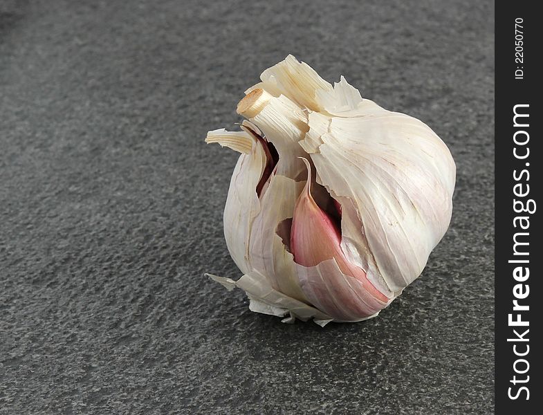 A garlic bulb on a dark textured background. A garlic bulb on a dark textured background.