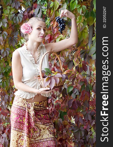 Beautiful girl in a long skirt with a basket of grapes outdoors shooting