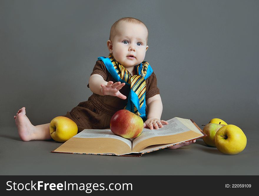 Portrait of the child on a gray background with the book and apples. Portrait of the child on a gray background with the book and apples