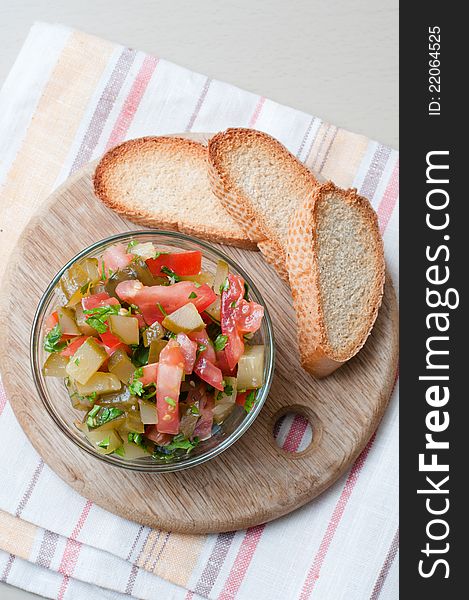 A bowl of salad made of cucumbers and tomatoes and croutons on a white plate.