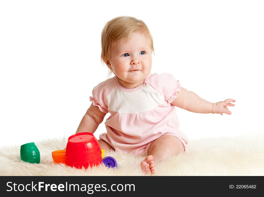 Cute little child is playing with toys while sitting on floor, isolated over white