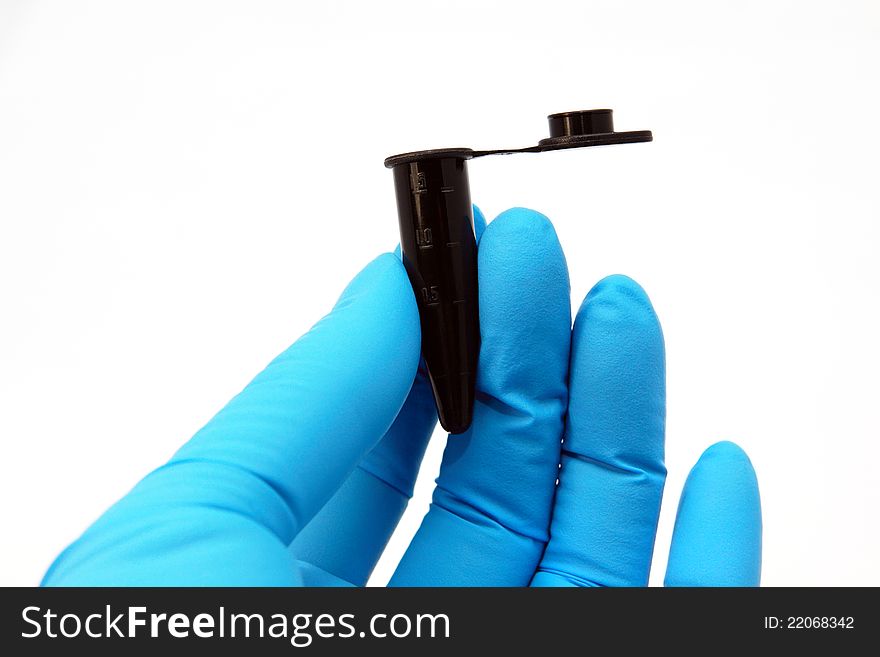 Arm in blue glove holds black micro tube. Arm in blue glove holds black micro tube