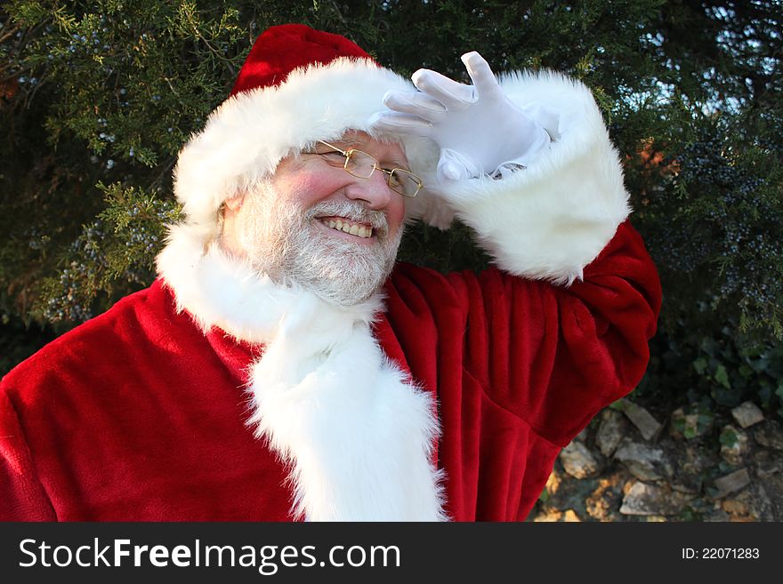 Smiling Santa holding his gloved hand over his eyes as he peers into the distance. Smiling Santa holding his gloved hand over his eyes as he peers into the distance.