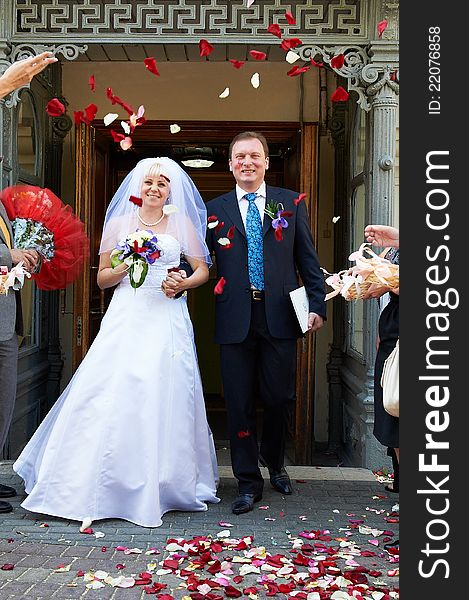 Happy newlyweds and flying red and white petals. Happy newlyweds and flying red and white petals