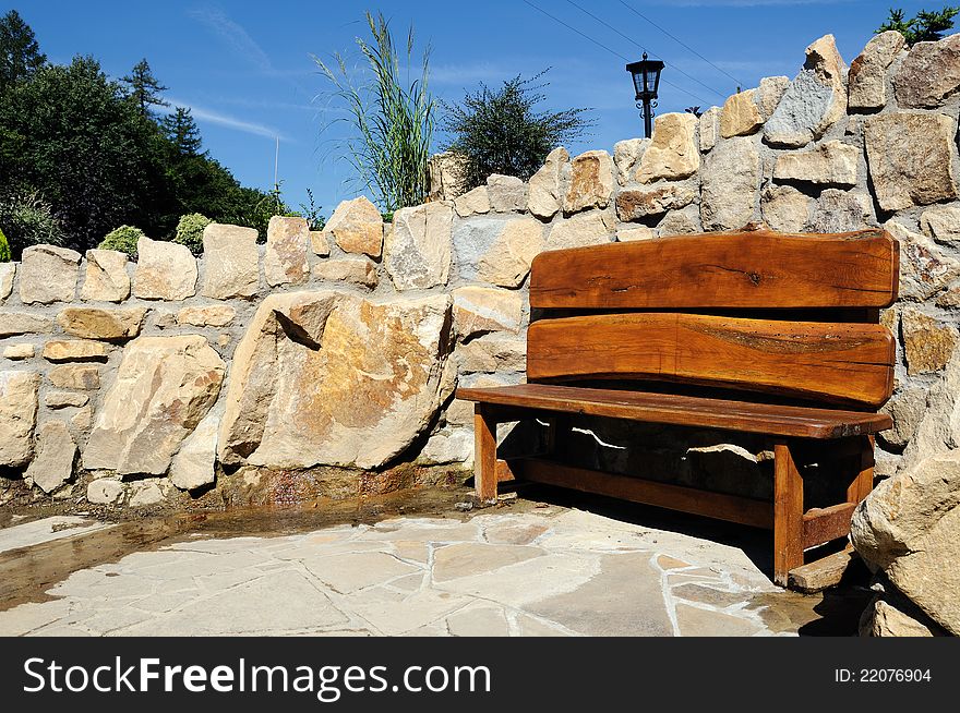 Wooden bench with a stone wall in background