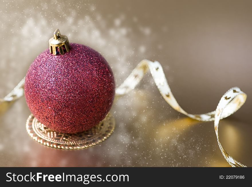 Christmas ball with gold ribbon bow with snow on a gold background
