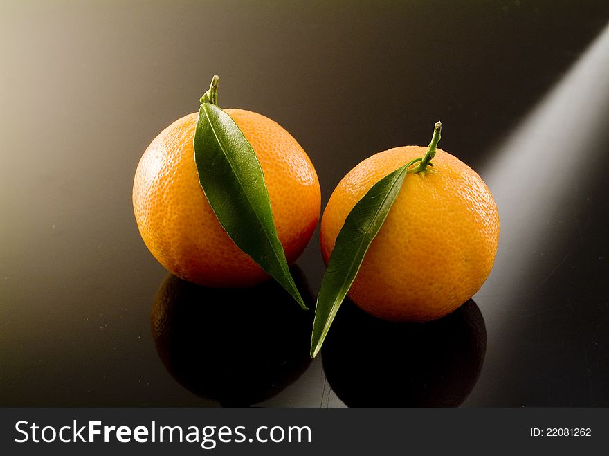 Mature mandarins with green leaf on a black background