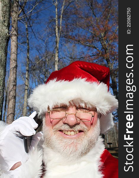 Santa making a call on his cell phone in an outdoor setting. Santa making a call on his cell phone in an outdoor setting.