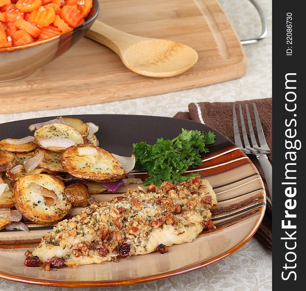 Cashew catfish fillet with potatoes and bowl of carrots in background. Cashew catfish fillet with potatoes and bowl of carrots in background