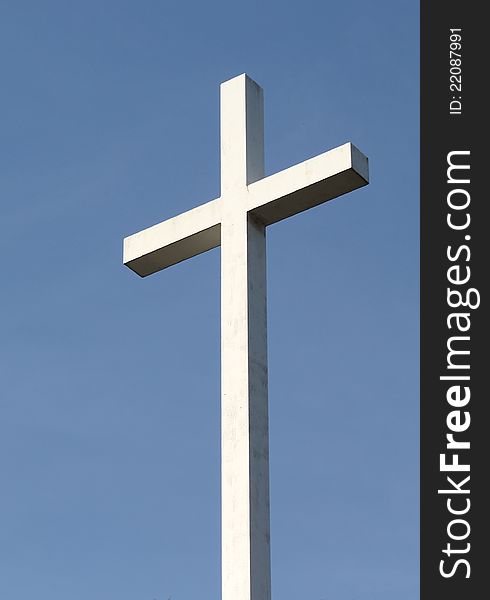 A white Christian cross stands out  against a deep blue blue sky. A white Christian cross stands out  against a deep blue blue sky.