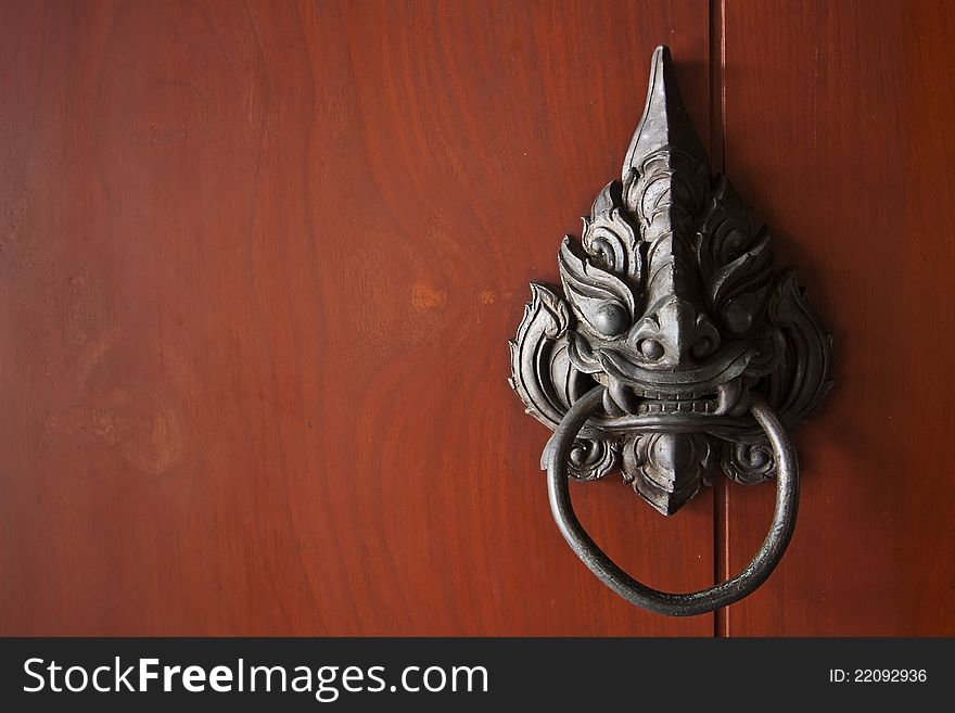 Antique door knocker in red wood background. Antique door knocker in red wood background.