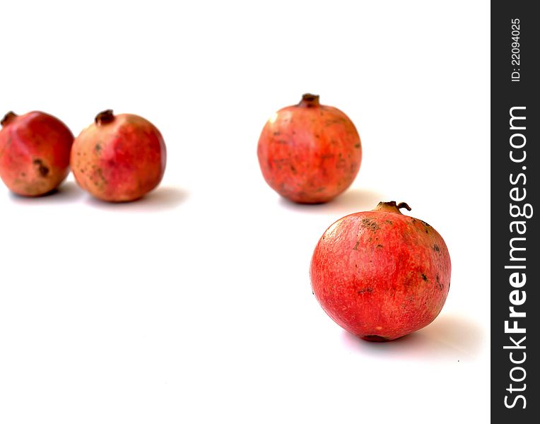 A pomegranate fruit with several of its peers in the background. A pomegranate fruit with several of its peers in the background