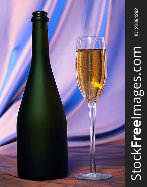 Glass of champagne and bottle.Blue background