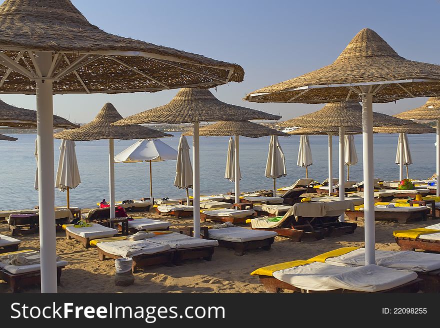 Deck chairs under an umbrella on a beach in the hot afternoon sun (Red Sea, Egypt). Deck chairs under an umbrella on a beach in the hot afternoon sun (Red Sea, Egypt)