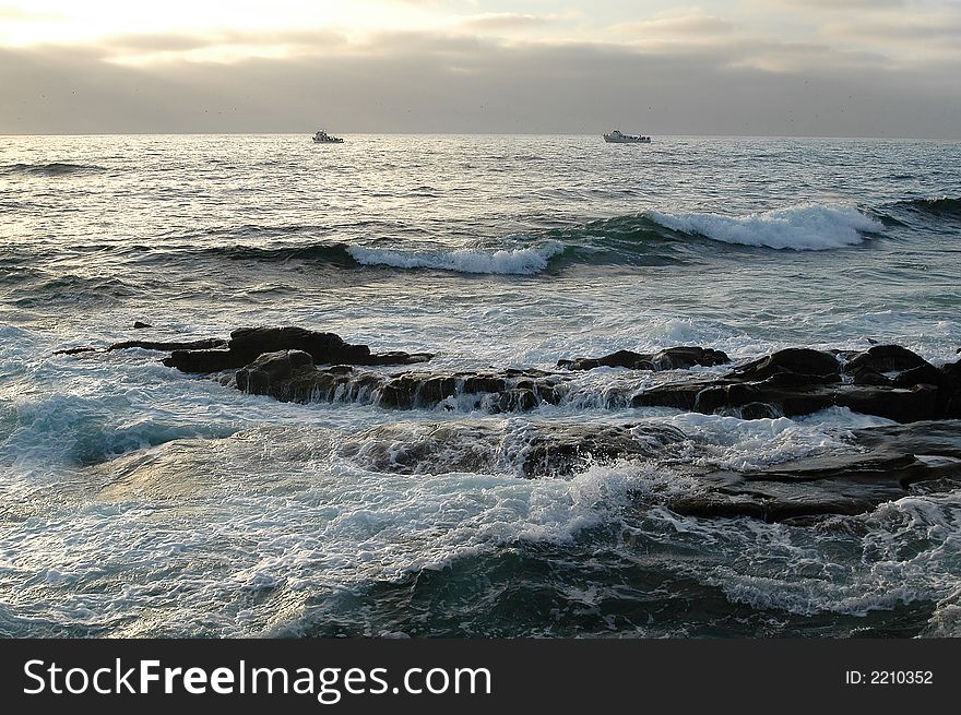 Sunset at theSan Diego ocean with boats and rock in the foreground. Sunset at theSan Diego ocean with boats and rock in the foreground