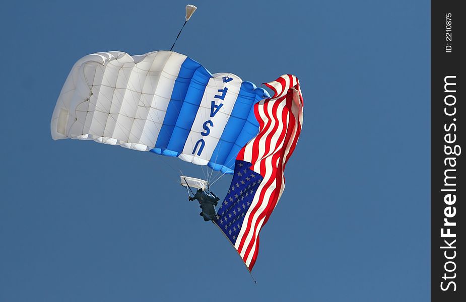 A USAF parachute jumper trails an american flag at an airshow