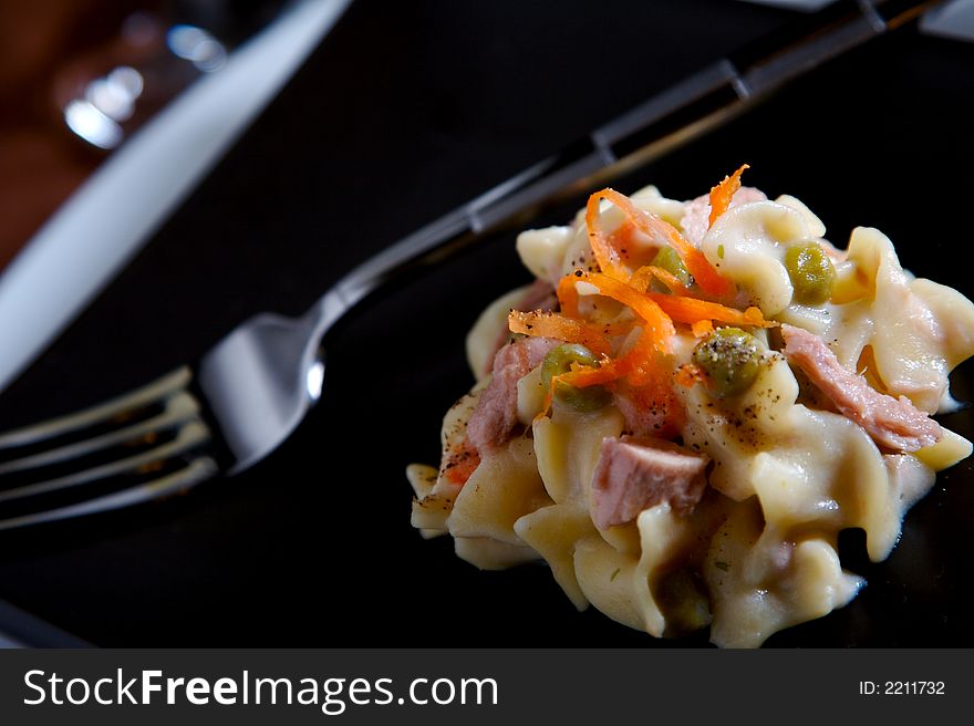 Tuna Noodle Casserole with peas and carrots on a black plate. Tuna Noodle Casserole with peas and carrots on a black plate.