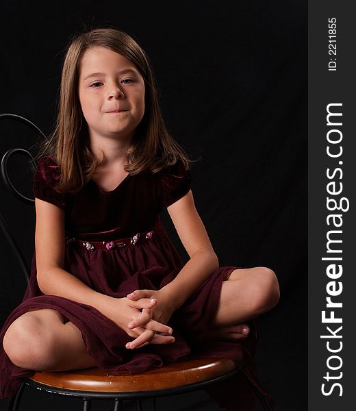 Brunette little girl sitting on a chair. Brunette little girl sitting on a chair