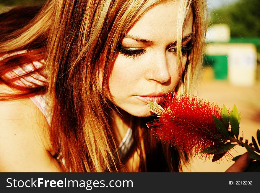 A woman is smelling a red flower. A woman is smelling a red flower