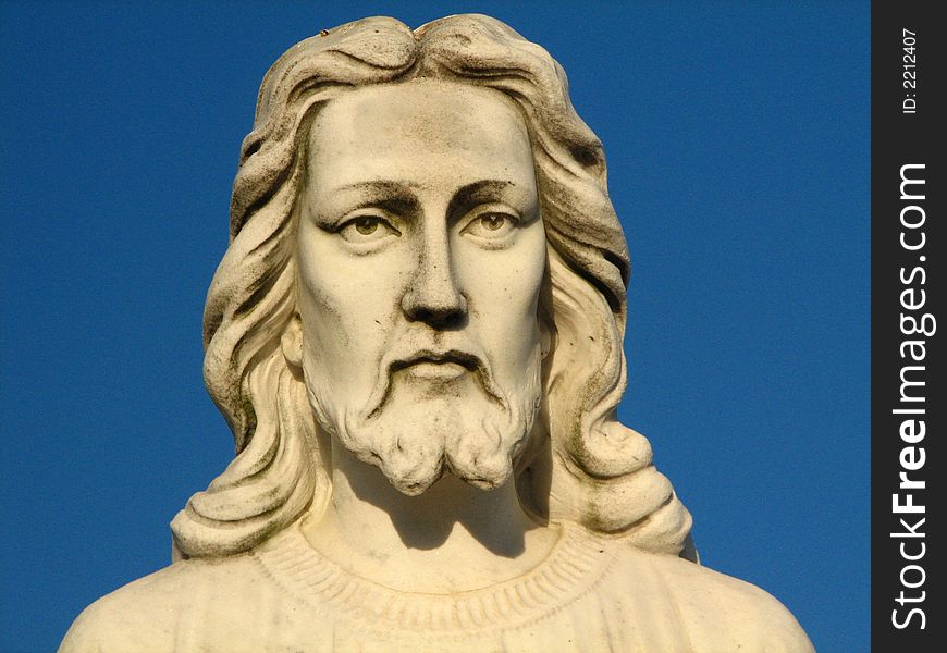 A statue of Jesus from the shoulders up with a blue sky in the background. A statue of Jesus from the shoulders up with a blue sky in the background.