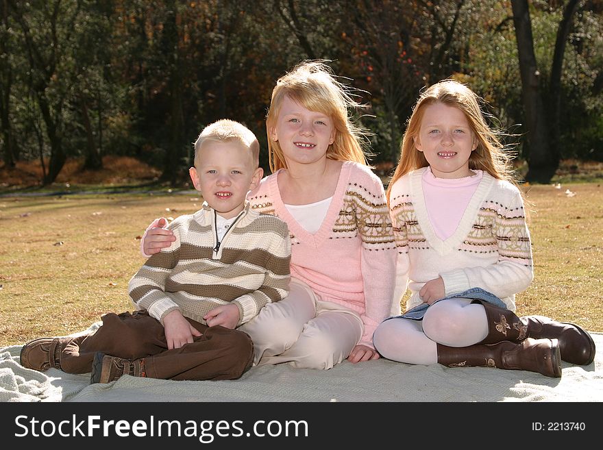 Two sisters and their brother sitting on the grass. Two sisters and their brother sitting on the grass
