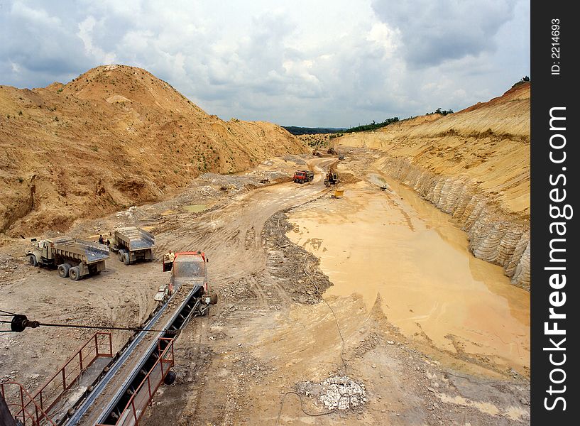 The Crushed stone, pouring elevated conveyor onto a dump truck against blue sky. The Crushed stone, pouring elevated conveyor onto a dump truck against blue sky