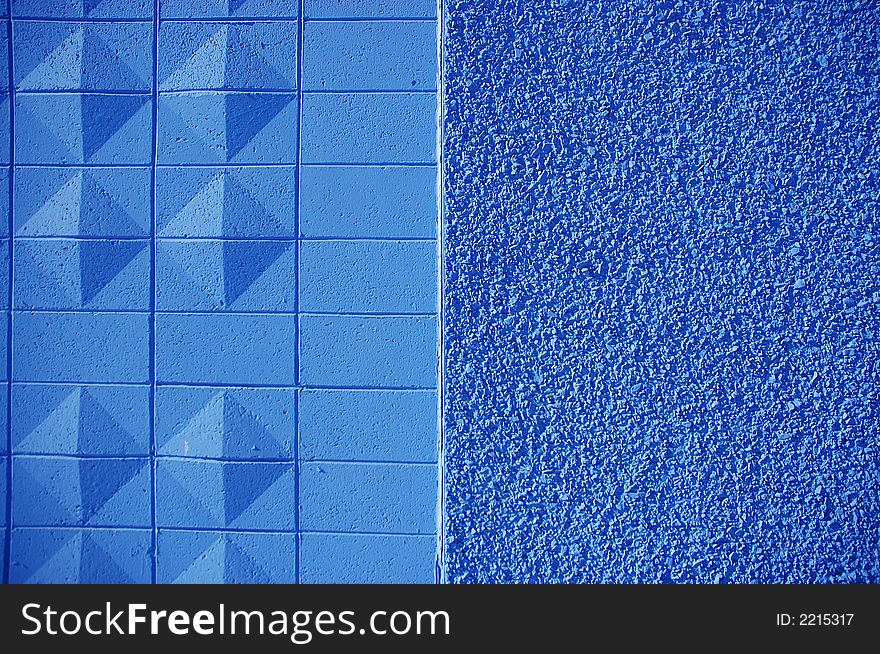 A blue painted wall with textured bricks and stone. A blue painted wall with textured bricks and stone