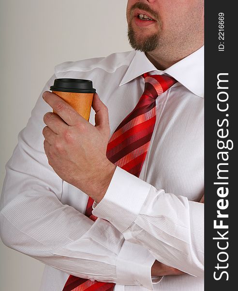 A man holding a cup of coffee on break chatting with someone. A man holding a cup of coffee on break chatting with someone