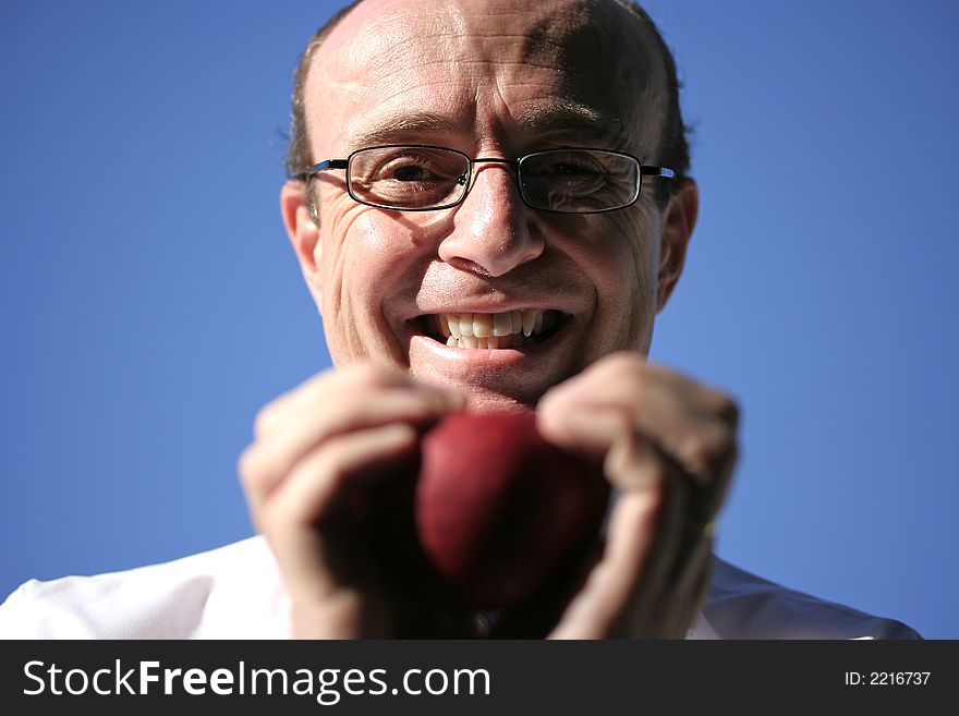 Doctor grasping a bright red apple between both hands about to eat it. Doctor grasping a bright red apple between both hands about to eat it