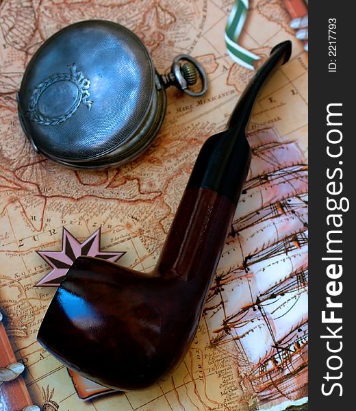 Tobacco-pipe and old watch on background atlas. Tobacco-pipe and old watch on background atlas